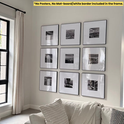 Wall with framed black and white pictures above a sofa in a room with a window and curtain.